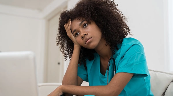 healthcare worker sitting on the ground with their eyes closed because of mental health challenges