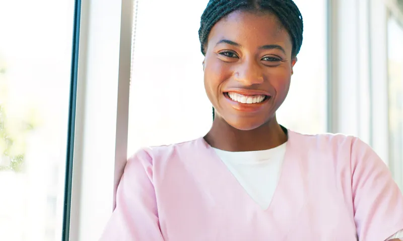 A healthcare professional wearing scrubs smiles