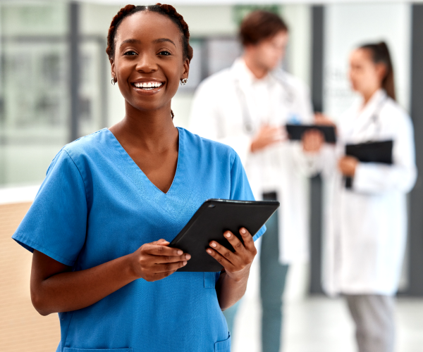 A healthcare professional holding a tablet smiling